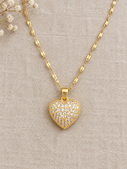Gold pavé heart pendant necklace lying flat on linen