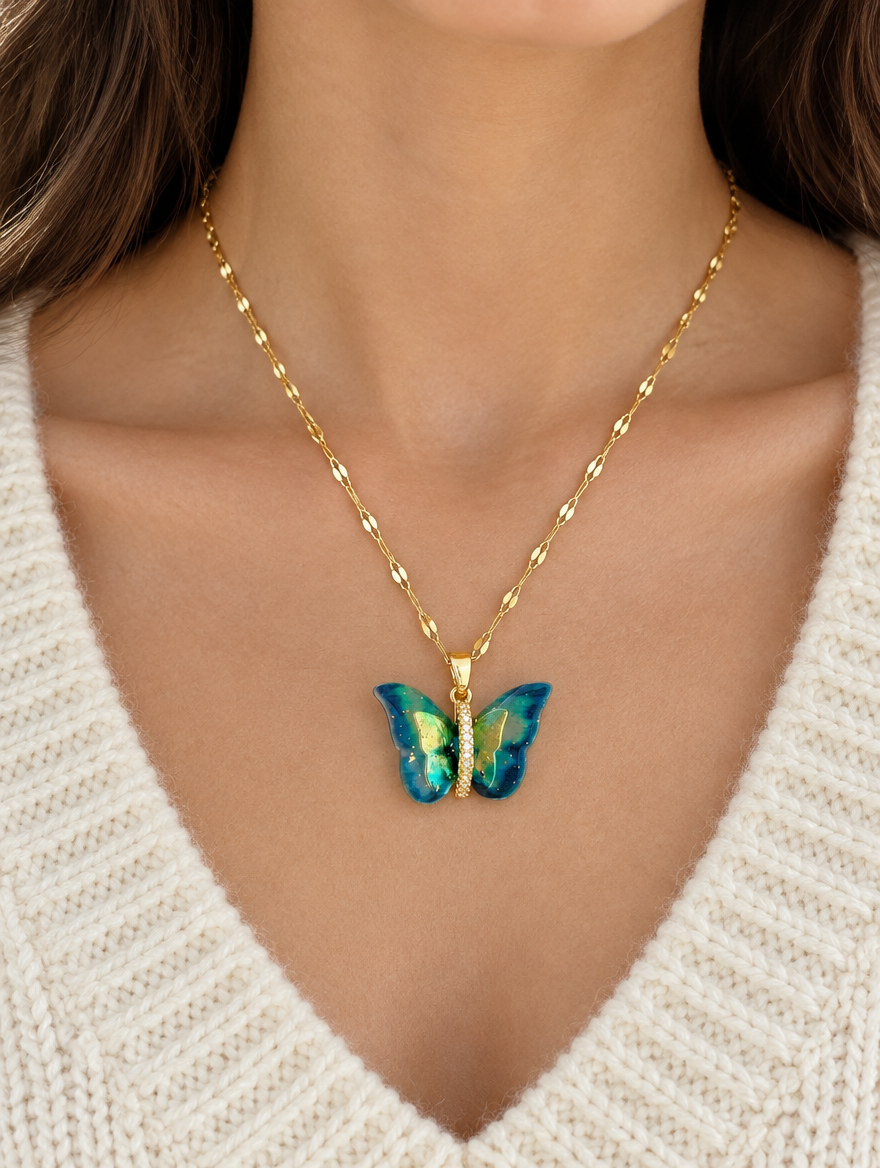 Woman wearing a gold enamel butterfly pendant necklace with a cream knit sweater