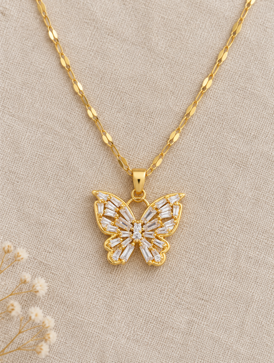 Gold crystal butterfly pendant necklace lying flat on linen