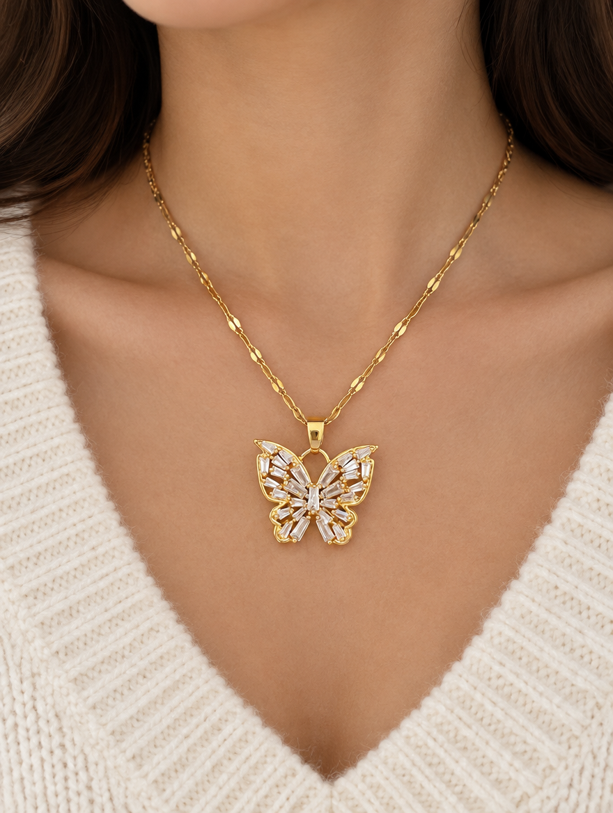 Woman wearing a gold crystal butterfly pendant necklace with a cream knit sweater