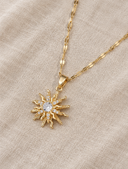 Gold sun pendant necklace lying flat on linen