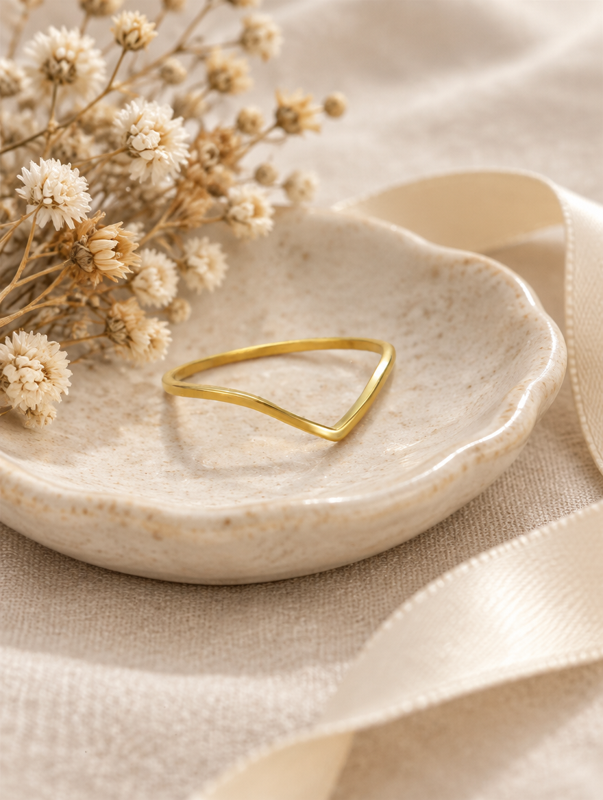 Gold slim chevron band ring in a small dish with styling props