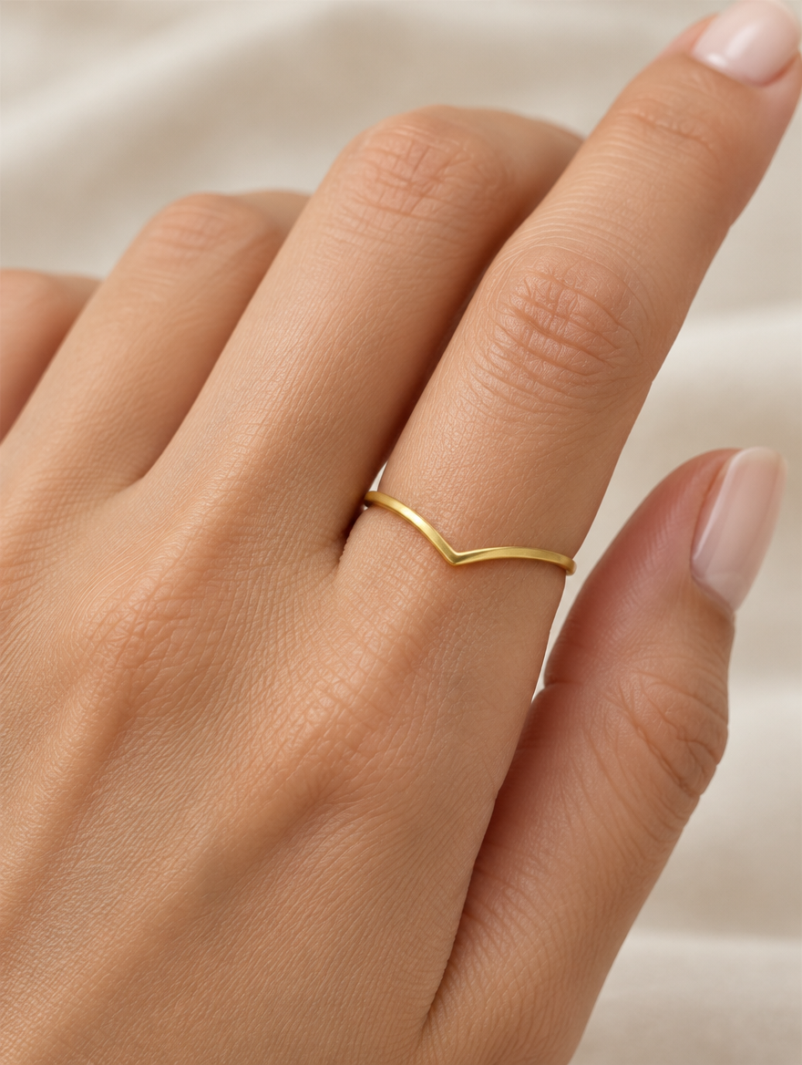 Woman wearing a gold slim chevron band ring on her finger