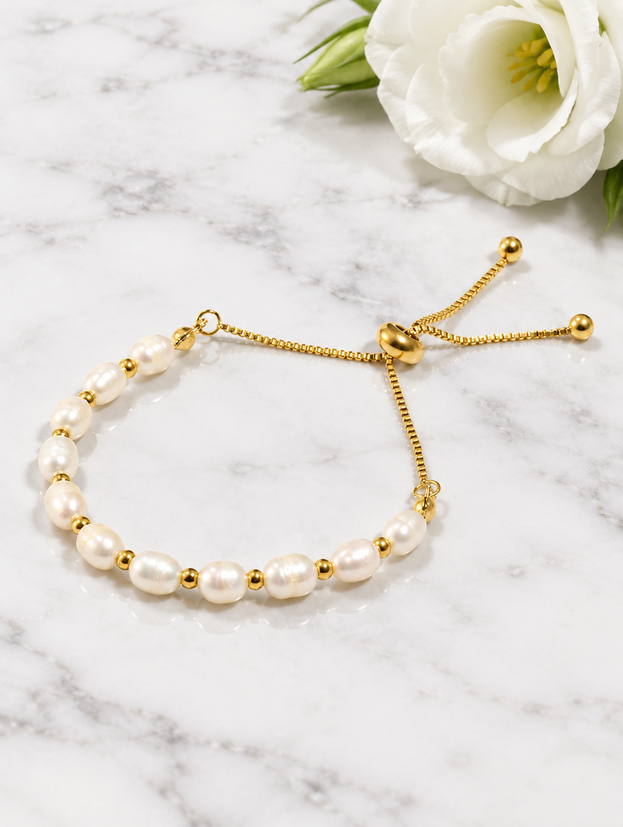 Freshwater pearl slider bracelet beside a white flower on marble