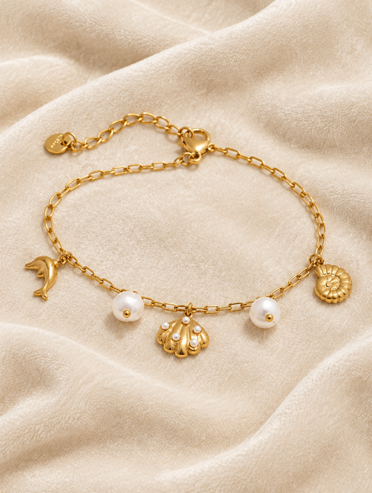 Gold-tone ocean charm bracelet on cream velvet