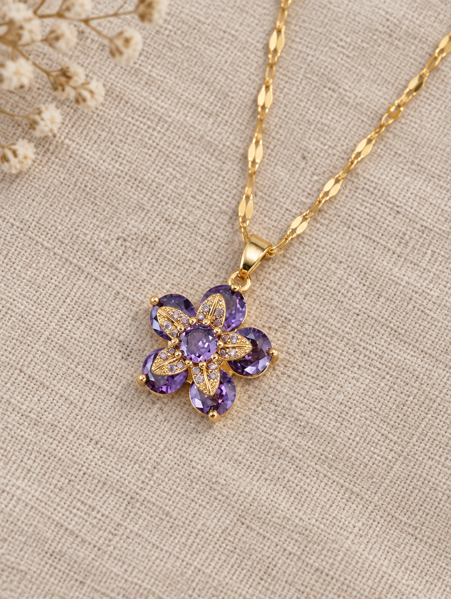 Gold purple flower pendant necklace lying flat on linen