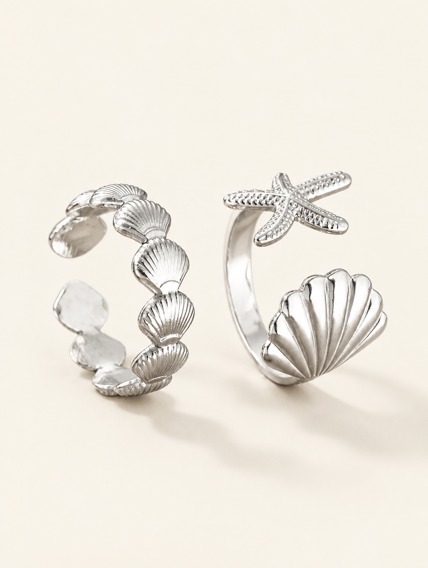 Set of two silver shell and starfish rings on a neutral background