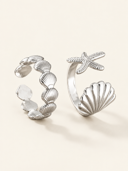 Set of two silver shell and starfish rings on a neutral background