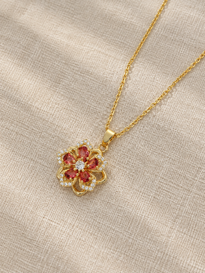 Gold red flower pendant necklace lying flat on linen