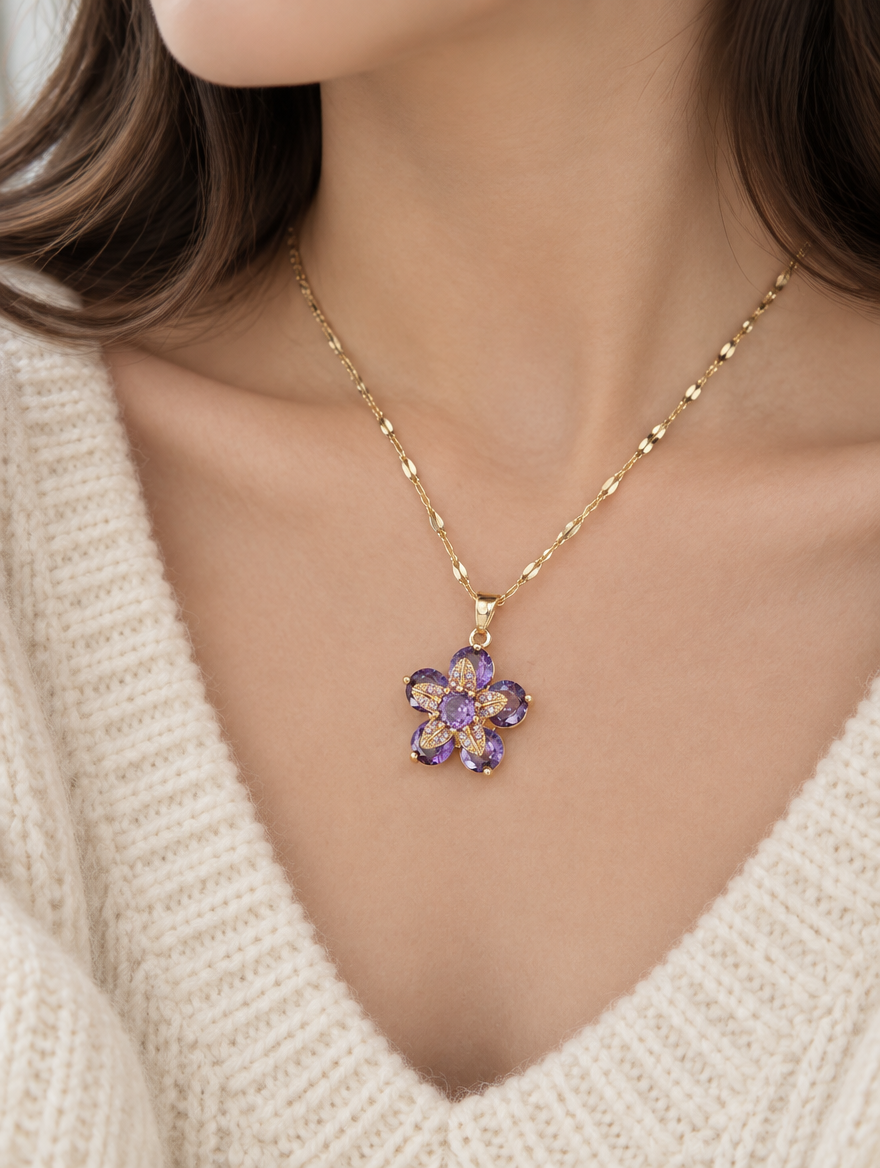 Woman wearing a gold purple flower pendant necklace with a cream knit sweater