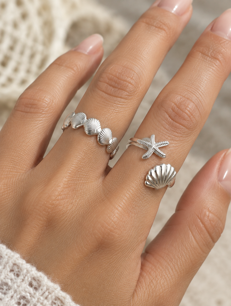 Woman wearing a set of two silver shell and starfish rings on her finger