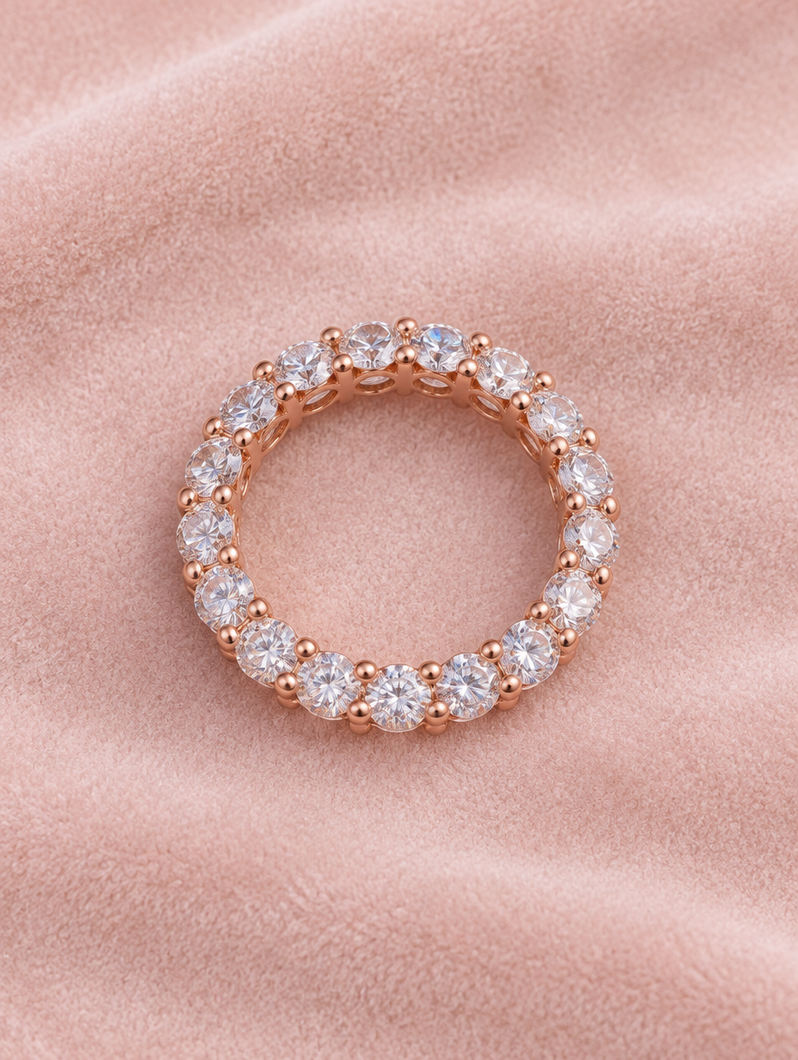 Rose gold zirconia eternity band ring resting on a soft textured surface